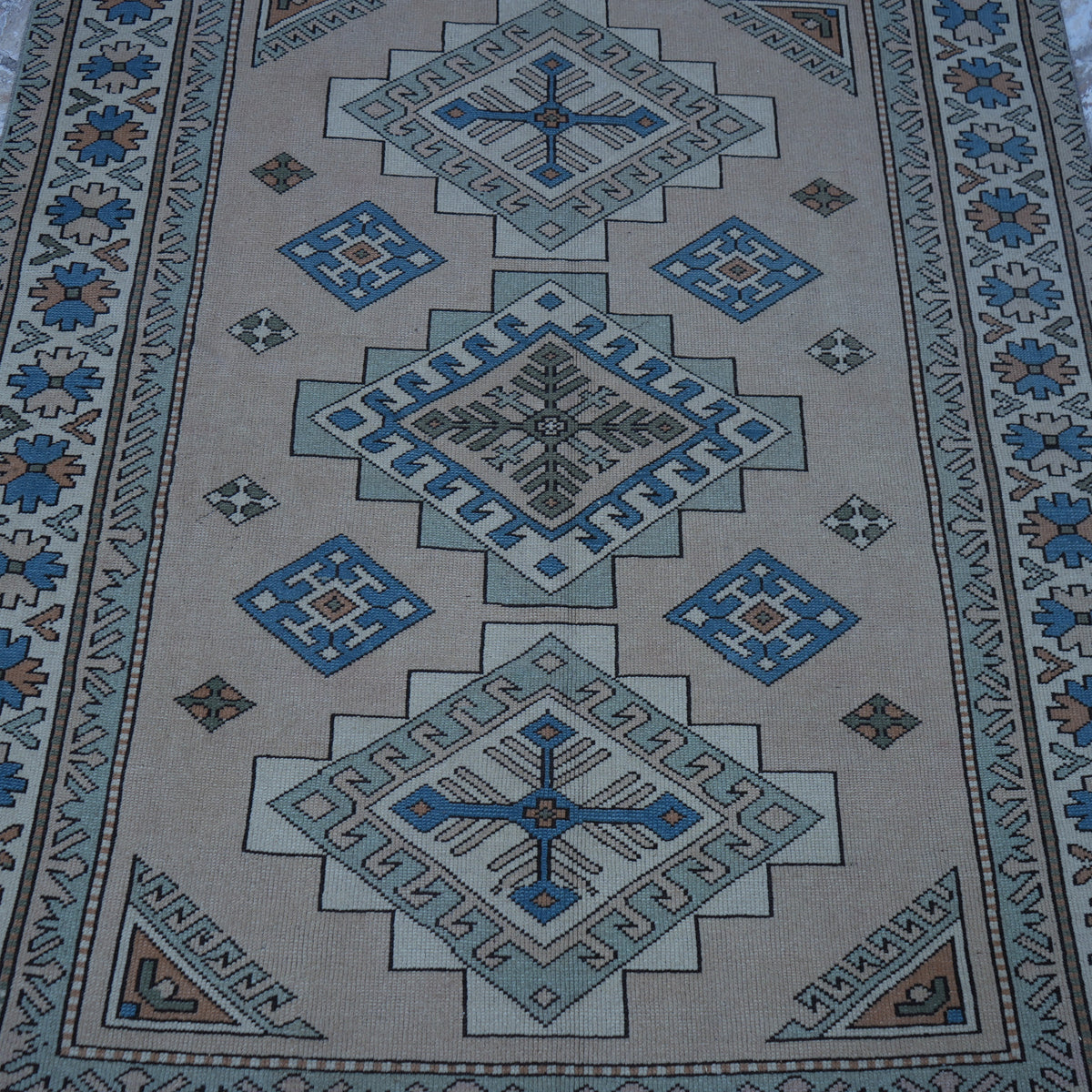 Close-up of the beige vintage Turkish geometric rug showing geometric details, hand-knotted weave, wool and low pile.
