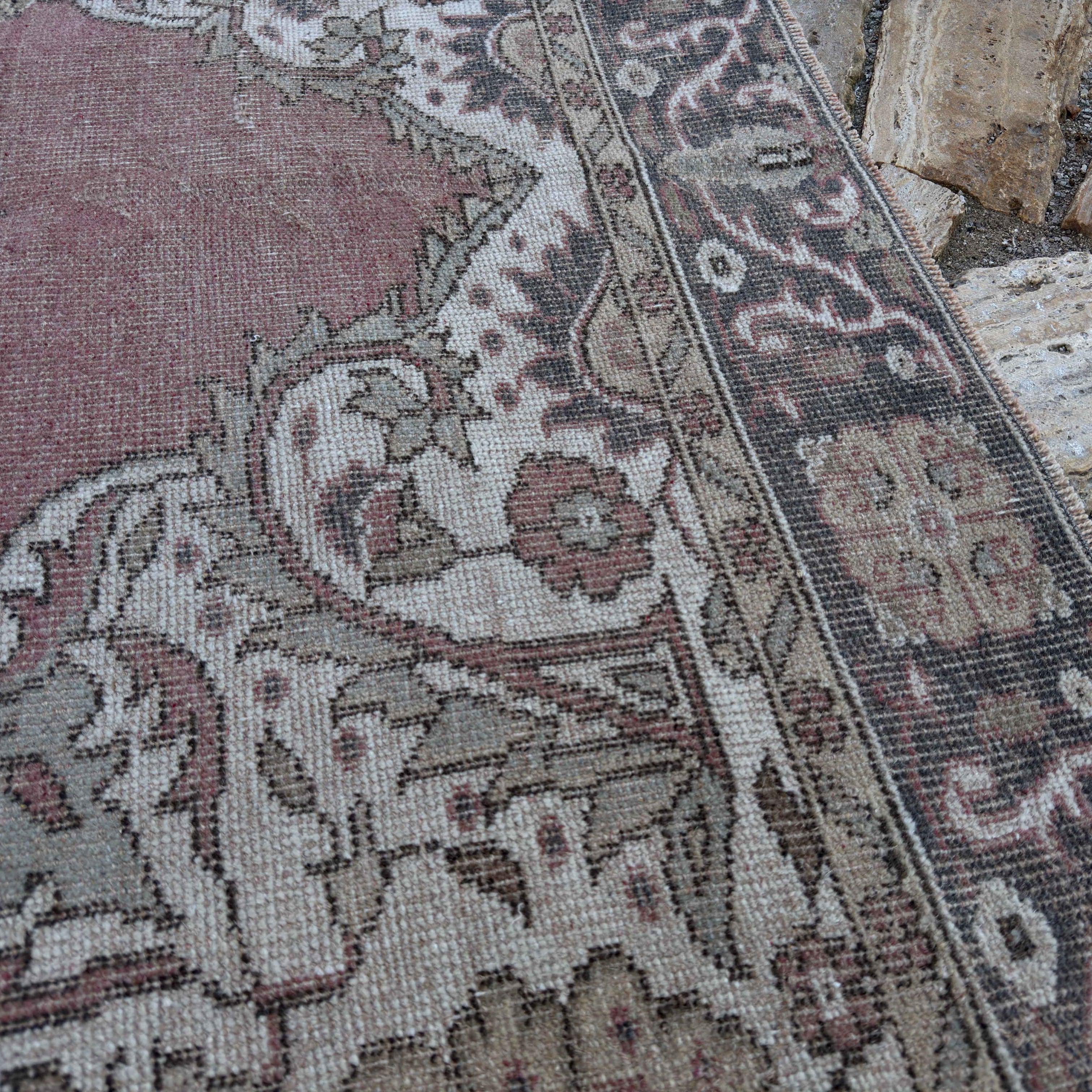 Close-up of the pale red vintage Turkish geometric rug showing medallion details, hand-knotted weave, wool and cotton and low pile.