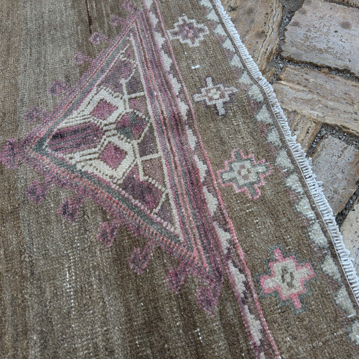 Close-up of the pale pink vintage Turkish kars area rug showing traditional details, hand-knotted weave, wool and cotton and low pile.