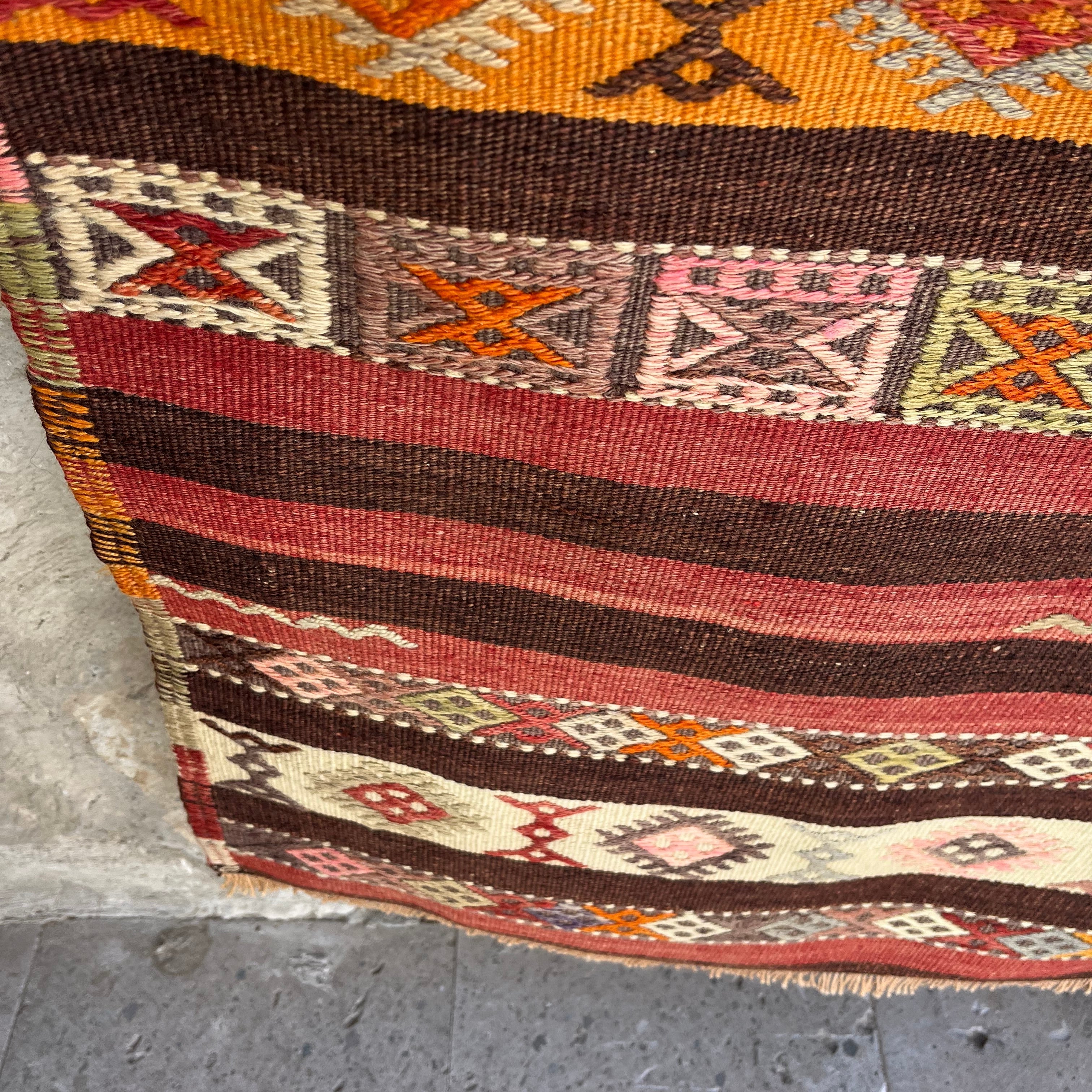 Close-up of the red vintage Turkish kilim rug showing traditional details, flatweave construction, wool and cotton and low pile.