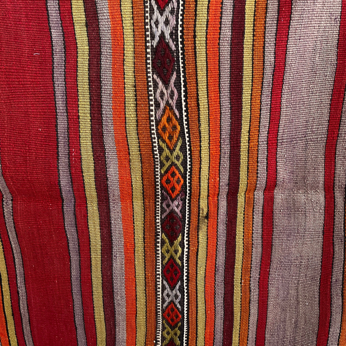Close-up of the red vintage Turkish kilim rug showing striped details, flatweave construction, wool and cotton and low pile.