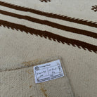 Close-up of the beige vintage Turkish kilim runner rug showing striped details, flatweave construction, wool and cotton and low pile.