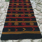 Black 3' x 11' vintage Turkish kilim runner rug in wool and cotton, shown on the floor.