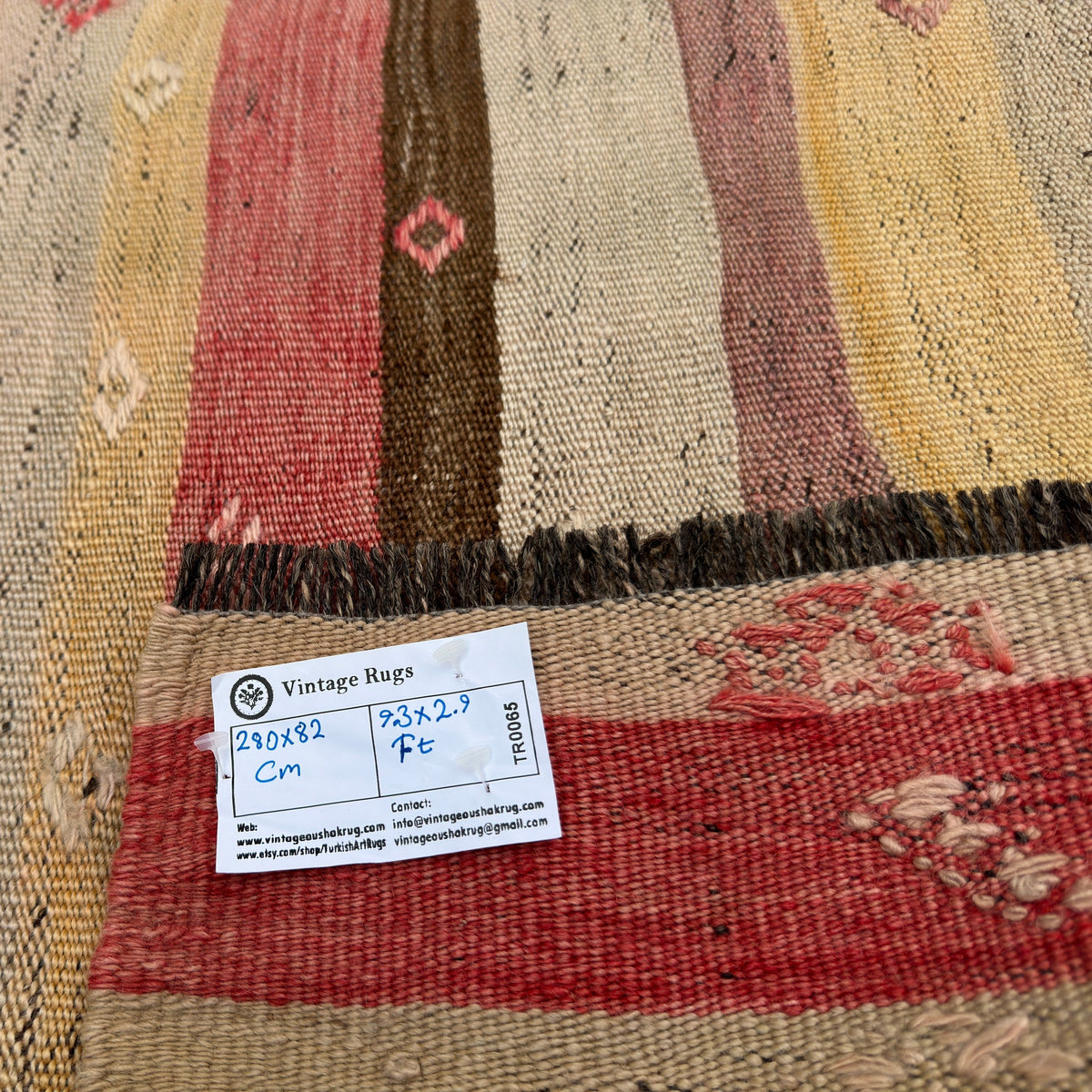 Close-up of the red vintage Turkish kilim runner rug showing striped details, flatweave construction, wool and cotton and low pile.
