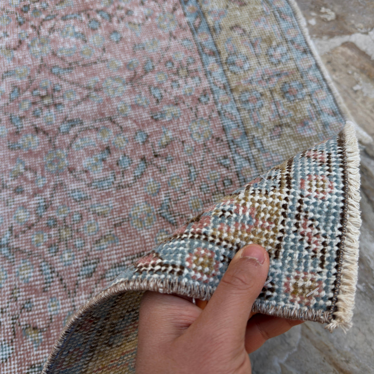 Close-up of the pink vintage Turkish large floral rug showing floral details, hand-knotted weave, wool and cotton and low pile.