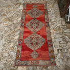 Red 5' x 12' vintage Turkish medallion carpet in wool, shown on the floor.