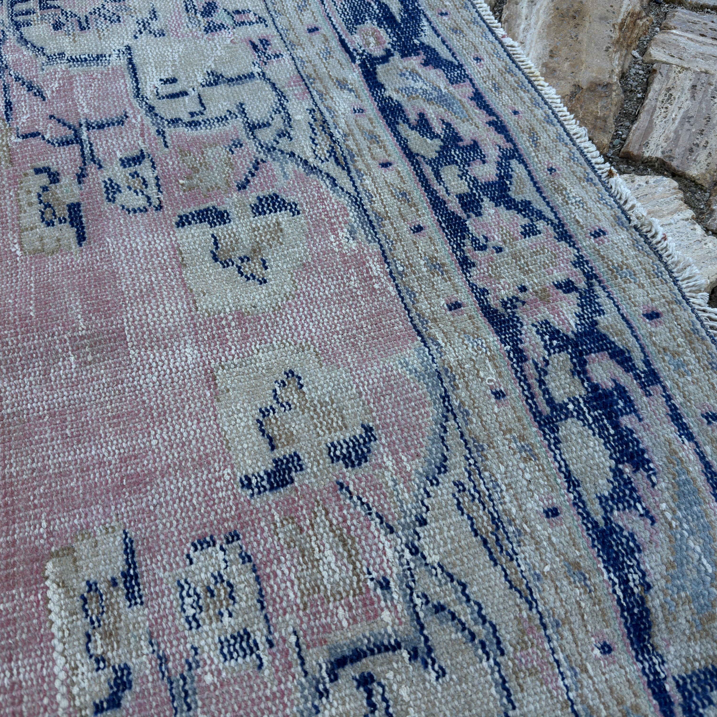 Close-up of the pale pink vintage Turkish medallion carpet showing medallion details, hand-knotted weave, wool and cotton and low pile.
