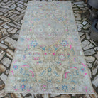 Pink 4' x 9' vintage Turkish medallion rug in wool and cotton, shown on the floor.