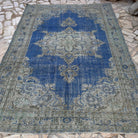 Blue 7' x 10' vintage Turkish medallion rug in wool and cotton, shown on the floor.