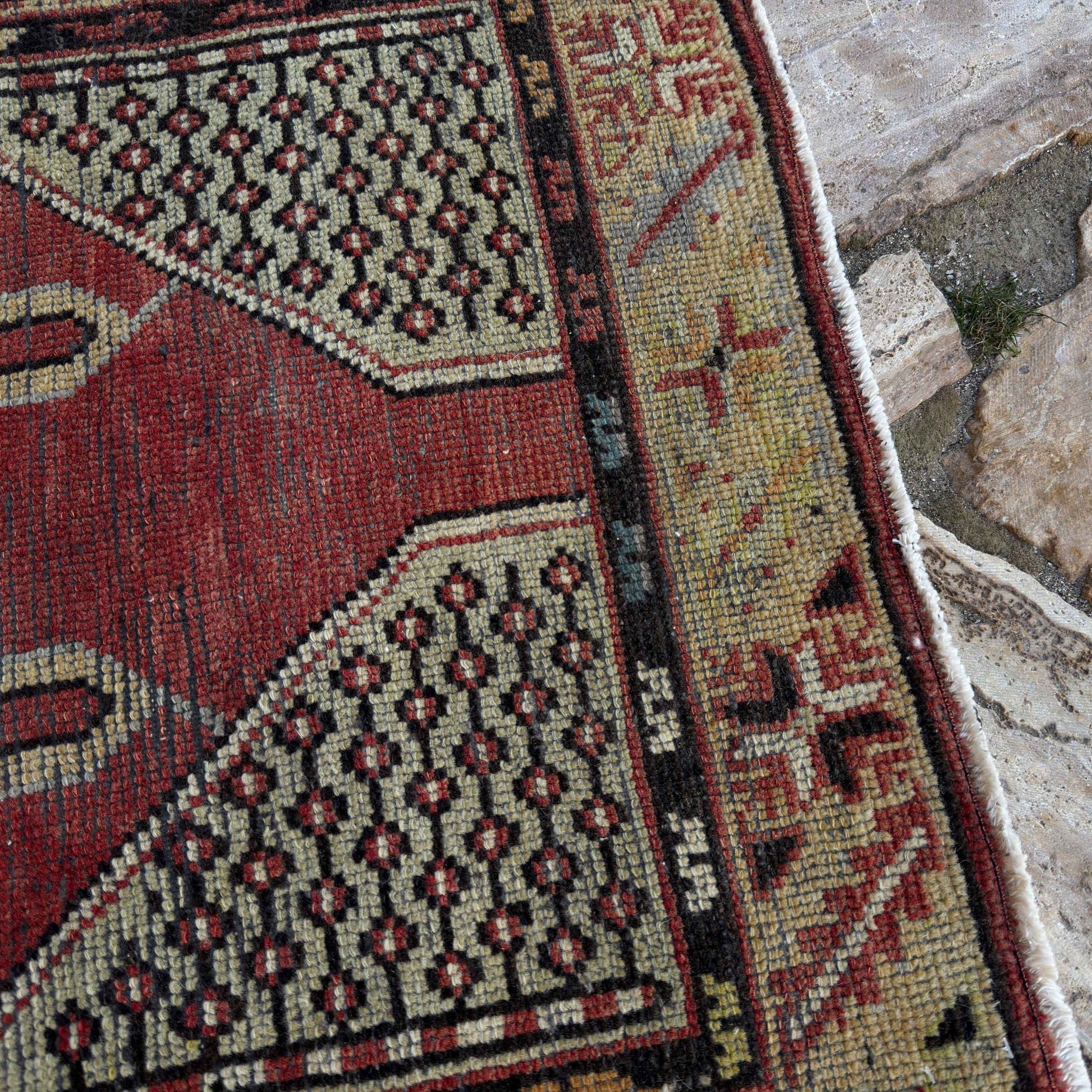 Close-up of the red vintage Turkish medium size rug showing medallion details, hand-knotted weave, wool and cotton and low pile.