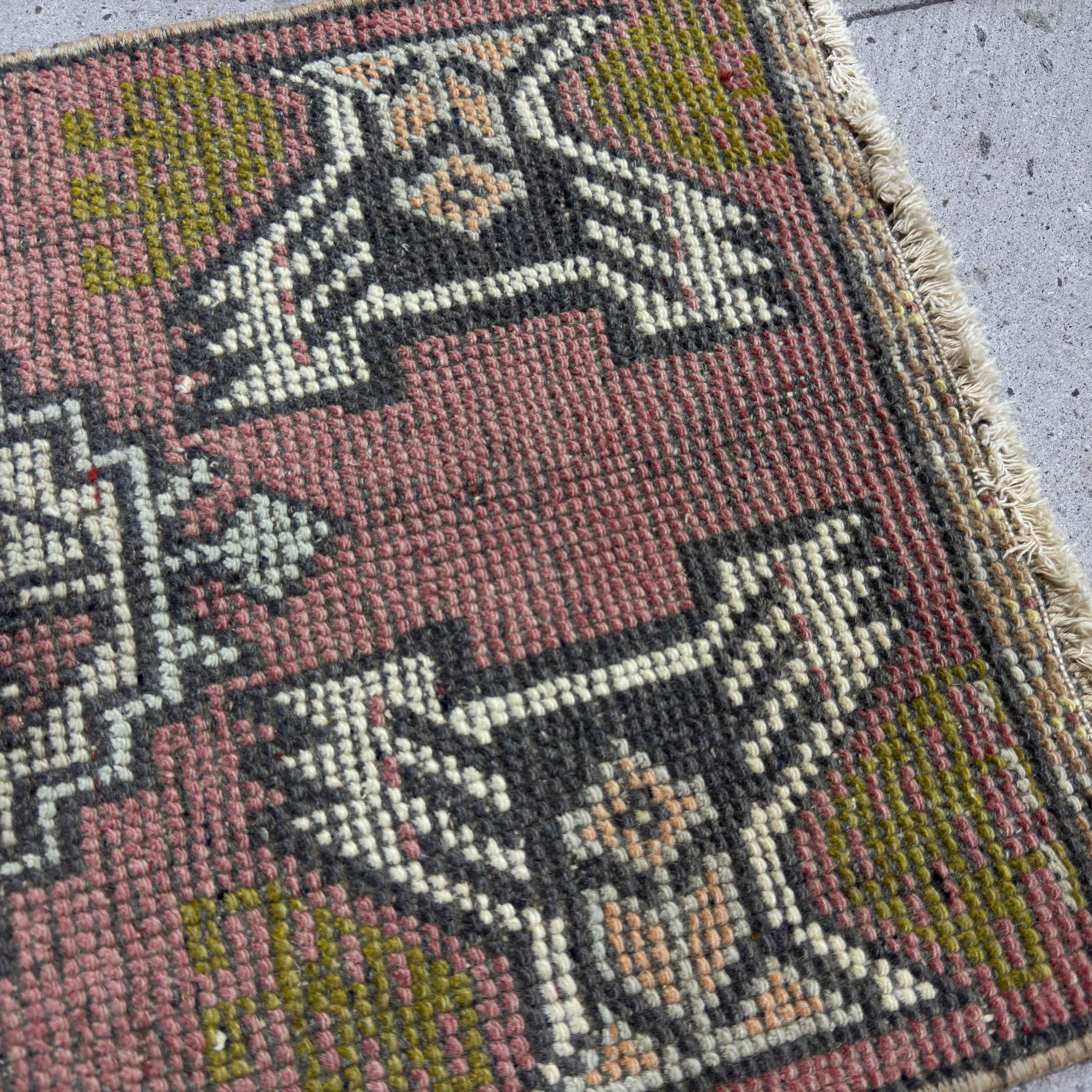 Close-up of the red vintage Turkish mini rug showing traditional details, hand-knotted weave, wool and cotton and low pile.