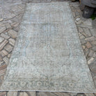 Beige 5' x 10' vintage Turkish muted rug in wool and cotton, shown on the floor.