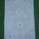 Close-up of the beige vintage Turkish neutral rug showing neutral details, hand-knotted weave, wool and cotton and low pile.