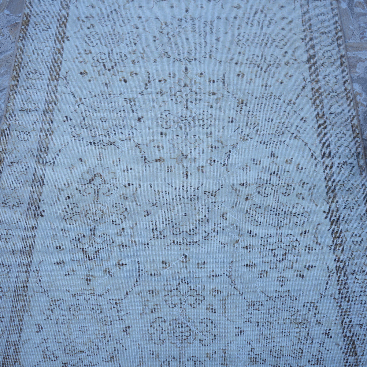 Close-up of the beige vintage Turkish neutral rug showing floral details, hand-knotted weave, wool and cotton and low pile.