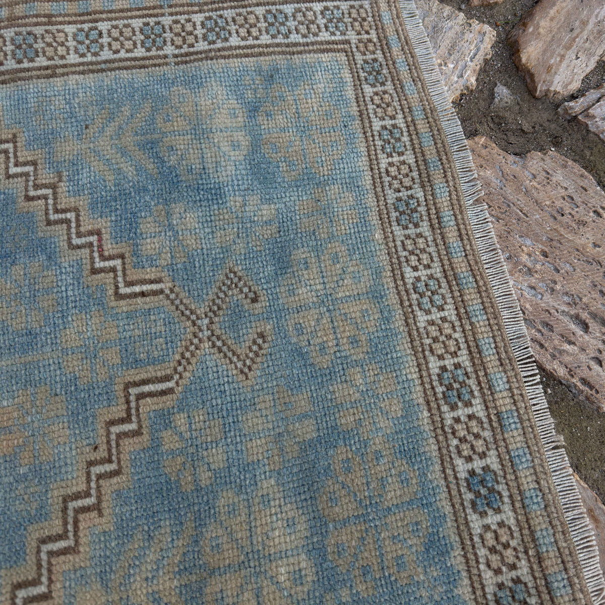 Close-up of the pale blue vintage Turkish oriental rug showing traditional details, hand-knotted weave, wool and cotton and low pile.
