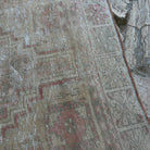 Close-up of the pale red vintage Turkish oriental rug showing neutral details, hand-knotted weave, wool and cotton and low pile.