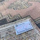 Close-up of the pink vintage Turkish oriental rug showing geometric details, hand-knotted weave, wool and cotton and low pile.