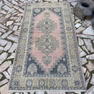 Pink 4' x 7' vintage Turkish oriental rug in wool and cotton, shown on the floor.
