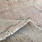 Close-up of the beige vintage Turkish oriental rug showing medallion details, hand-knotted weave, wool and cotton and low pile.