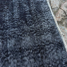 Close-up of the black vintage Turkish overdyed rug showing overdyed details, hand-knotted weave, wool and cotton and low pile.