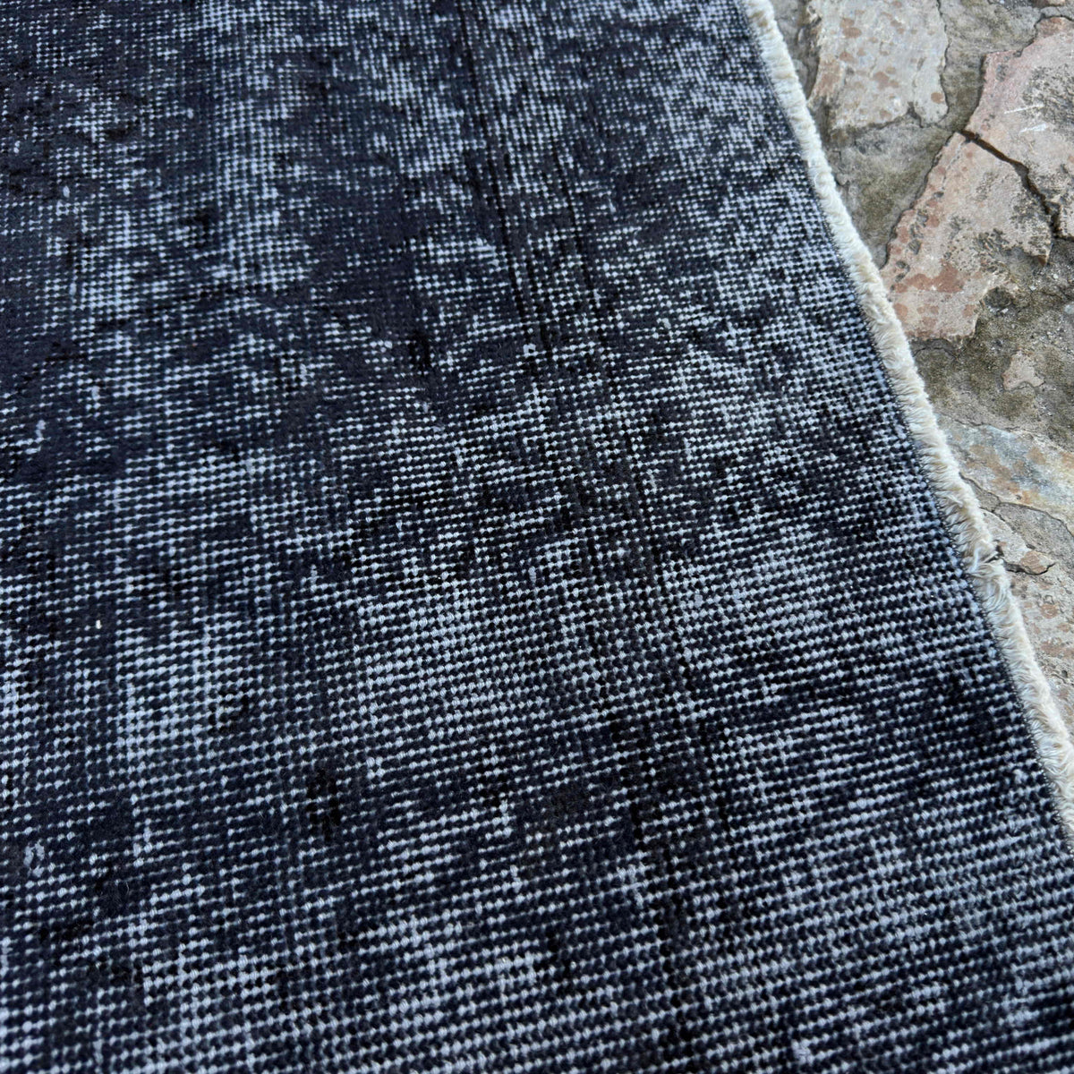 Close-up of the black vintage Turkish overdyed rug showing overdyed details, hand-knotted weave, wool and cotton and low pile.