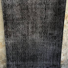 Black 4' x 10' vintage Turkish overdyed rug in wool and cotton, shown on the floor.