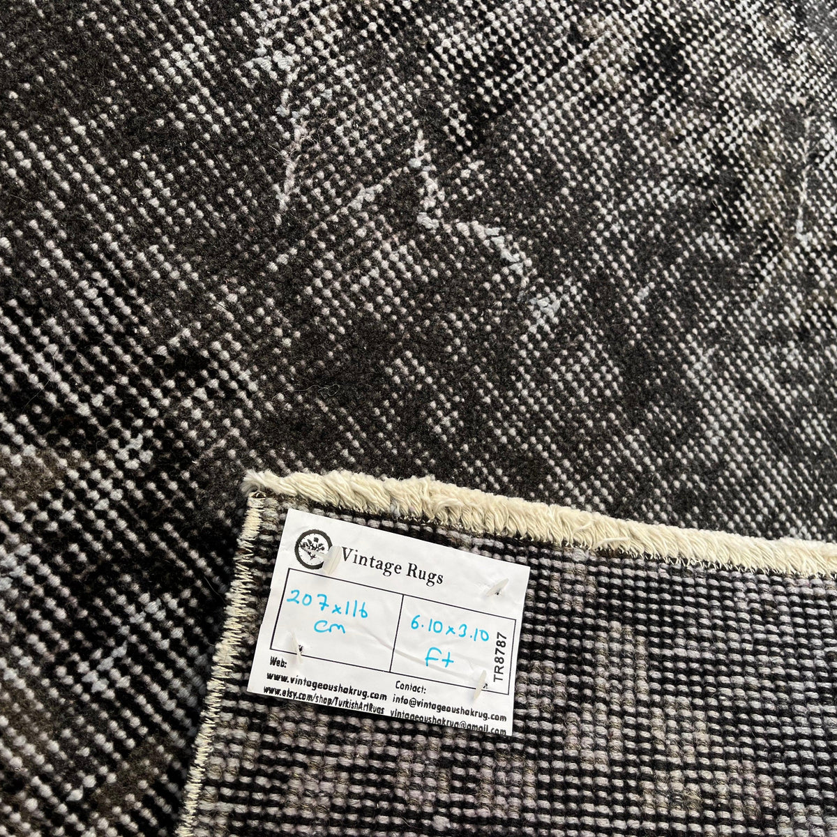 Close-up of the black vintage Turkish overdyed rug showing overdyed details, hand-knotted weave, wool and cotton and low pile.