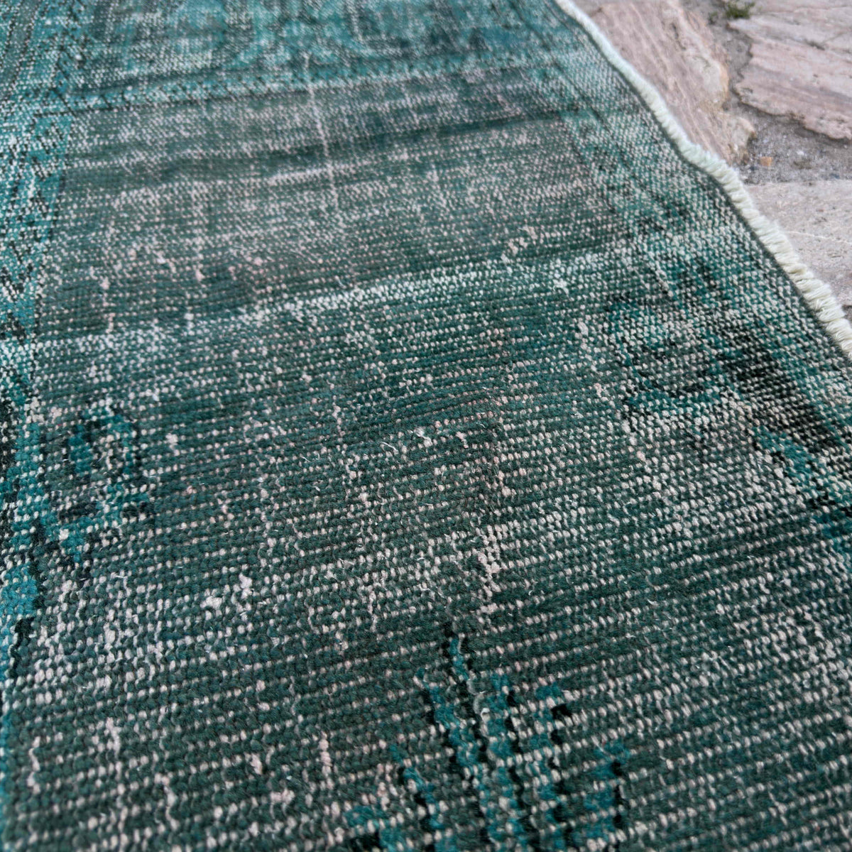 Close-up of the blue vintage Turkish overdyed rug showing overdyed details, hand-knotted weave, wool and cotton and low pile.
