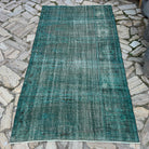 Blue 4' x 7' vintage Turkish overdyed rug in wool and cotton, shown on the floor.