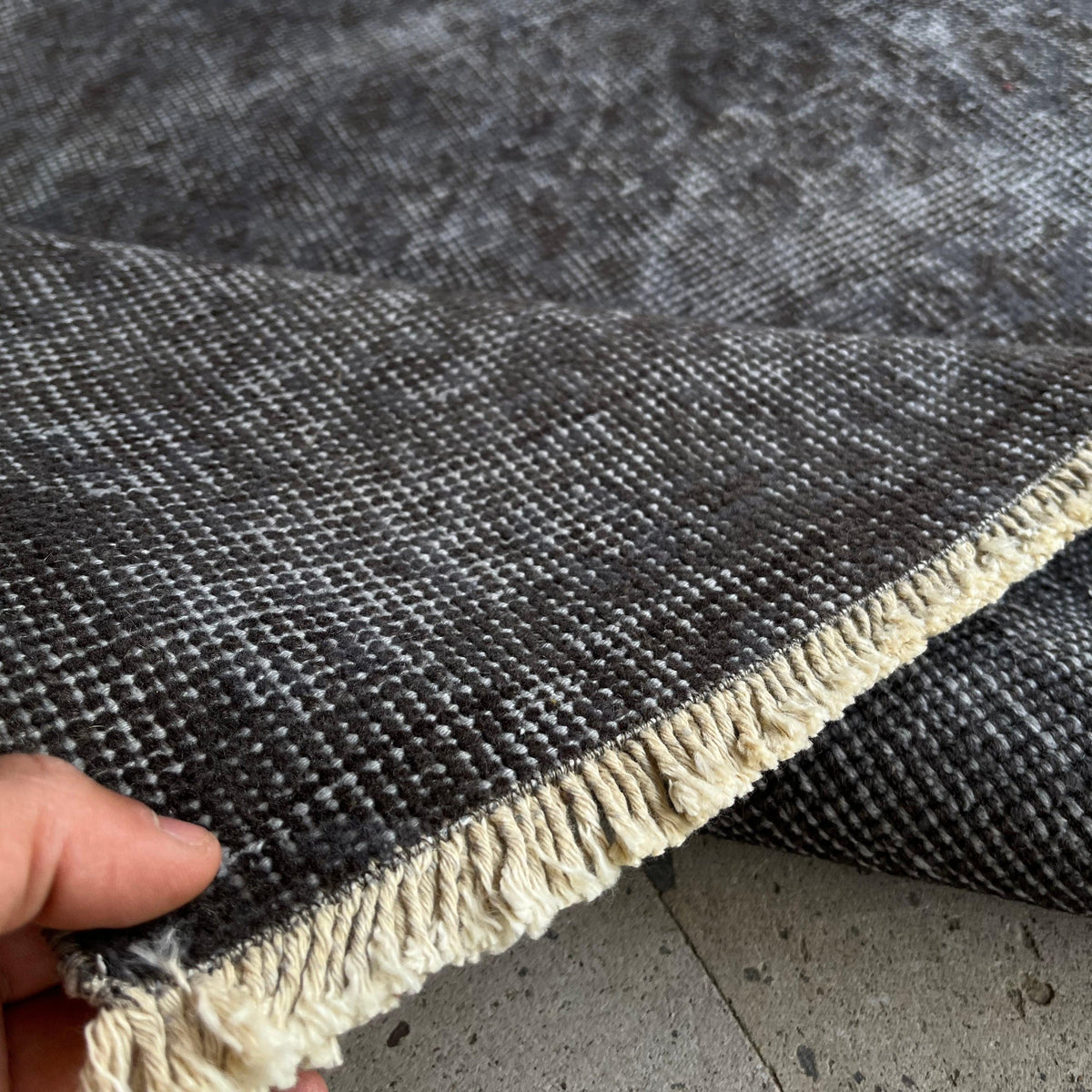 Close-up of the gray vintage Turkish overdyed rug showing overdyed details, hand-knotted weave, wool and cotton and low pile.