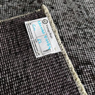Close-up of the gray vintage Turkish overdyed rug showing overdyed details, hand-knotted weave, wool and cotton and low pile.