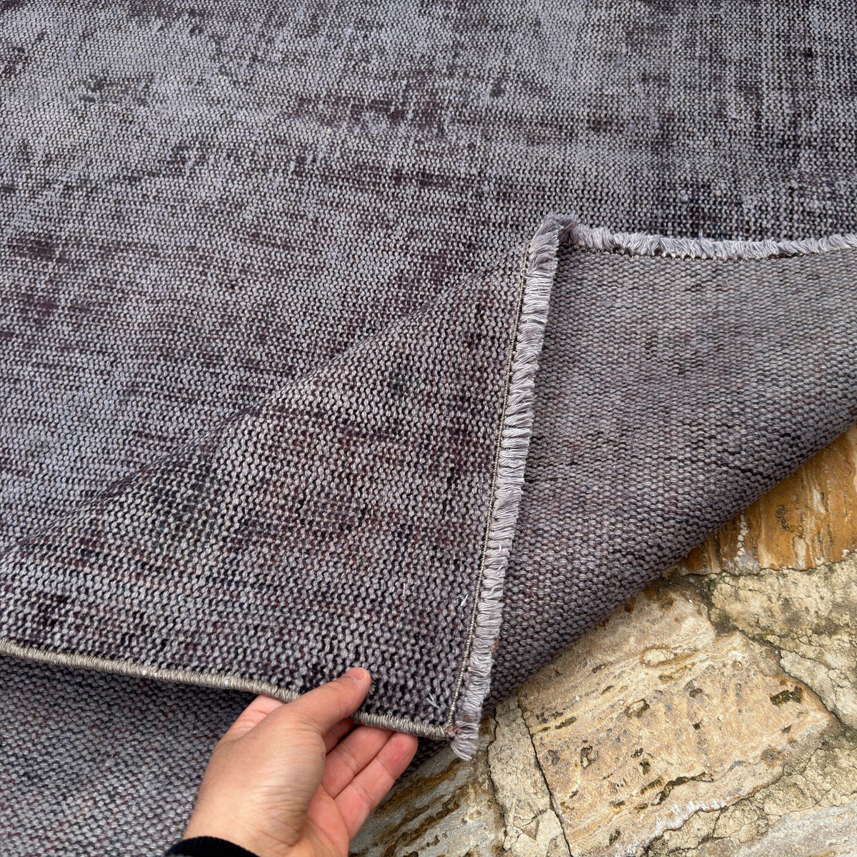 Close-up of the gray vintage Turkish overdyed rug showing overdyed details, hand-knotted weave, wool and cotton and low pile.