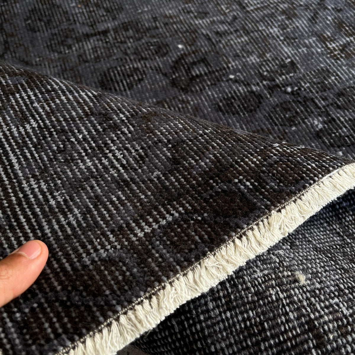 Close-up of the black vintage Turkish overdyed rug showing overdyed details, hand-knotted weave, wool and cotton and low pile.