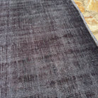 Close-up of the black vintage Turkish overdyed rug showing overdyed details, hand-knotted weave, wool and cotton and low pile.