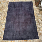 Black 7' x 10' vintage Turkish overdyed rug in wool and cotton, shown on the floor.