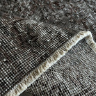 Close-up of the black vintage Turkish overdyed rug showing overdyed details, hand-knotted weave, wool and cotton and low pile.