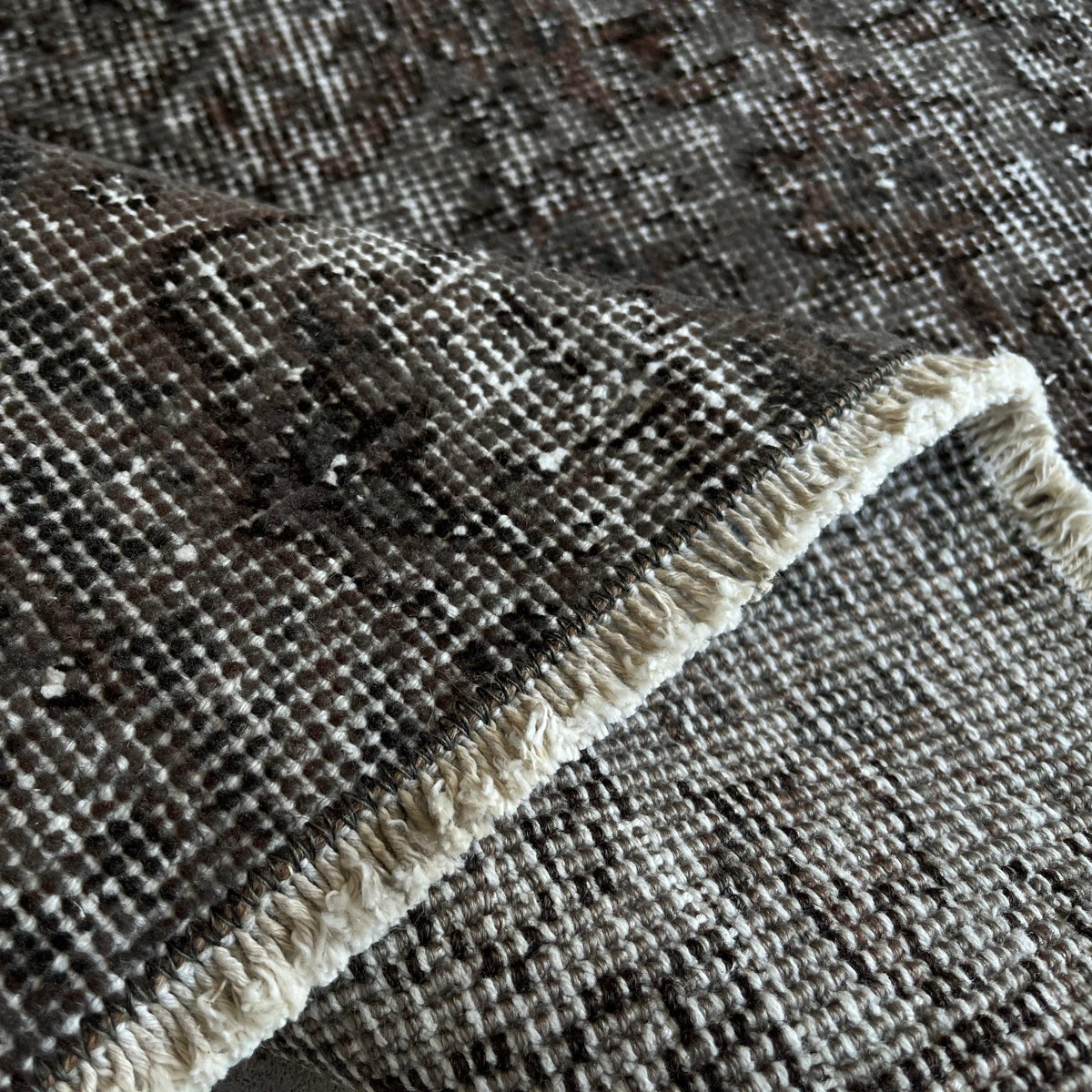 Close-up of the black vintage Turkish overdyed rug showing overdyed details, hand-knotted weave, wool and cotton and low pile.