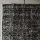 1970s black vintage Turkish overdyed rug with overdyed design, hand-knotted weave and low pile.