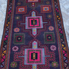 Close-up of the purple vintage Turkish persian rug showing geometric details, hand-knotted weave, wool and cotton and low pile.
