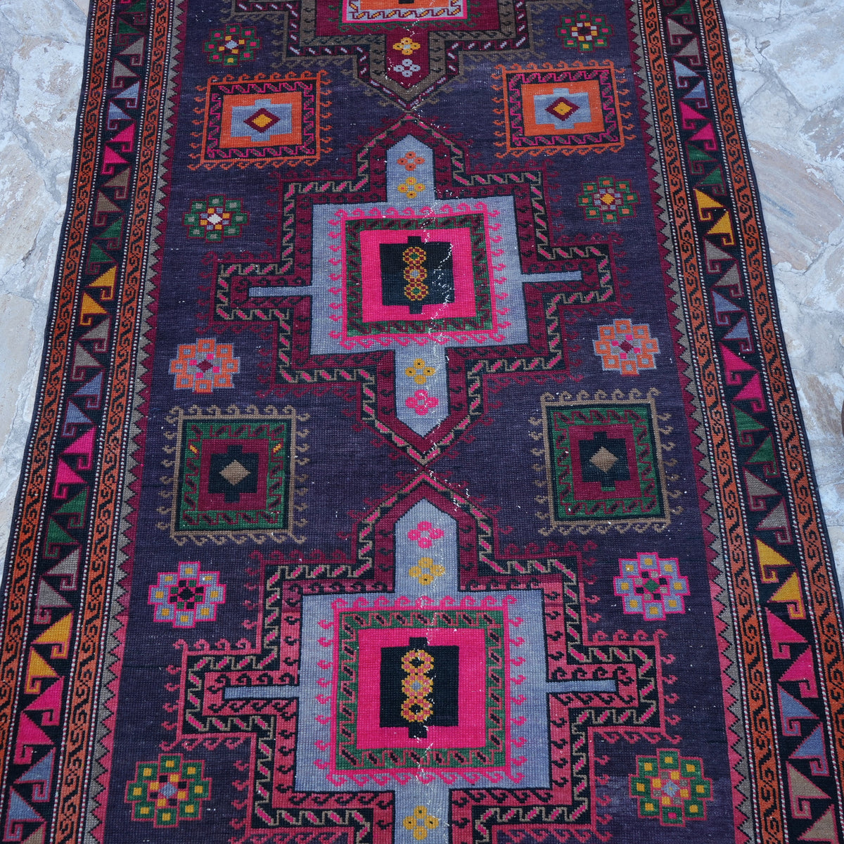 Close-up of the purple vintage Turkish persian rug showing geometric details, hand-knotted weave, wool and cotton and low pile.