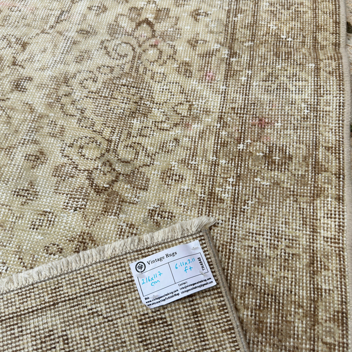 Close-up of the beige vintage persian rug showing floral details, hand-knotted weave, wool and cotton and low pile.