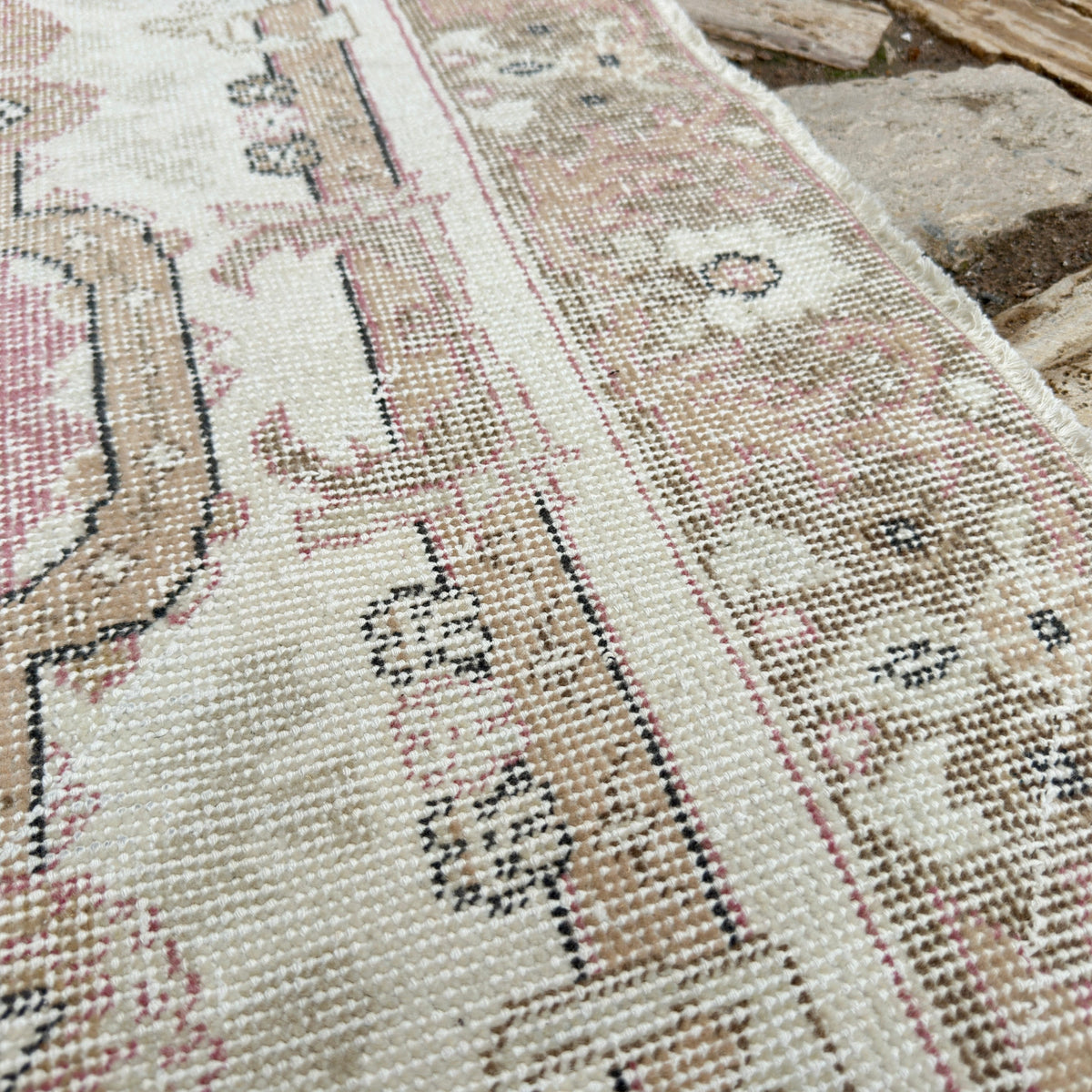 Close-up of the pink vintage Turkish persian rug showing medallion details, hand-knotted weave, wool and cotton and low pile.