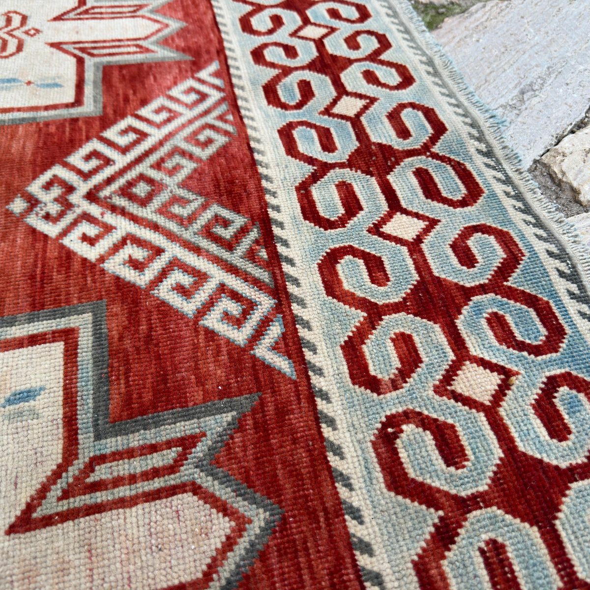 Close-up of the red vintage persian rug showing traditional details, hand-knotted weave, wool and cotton and low pile.