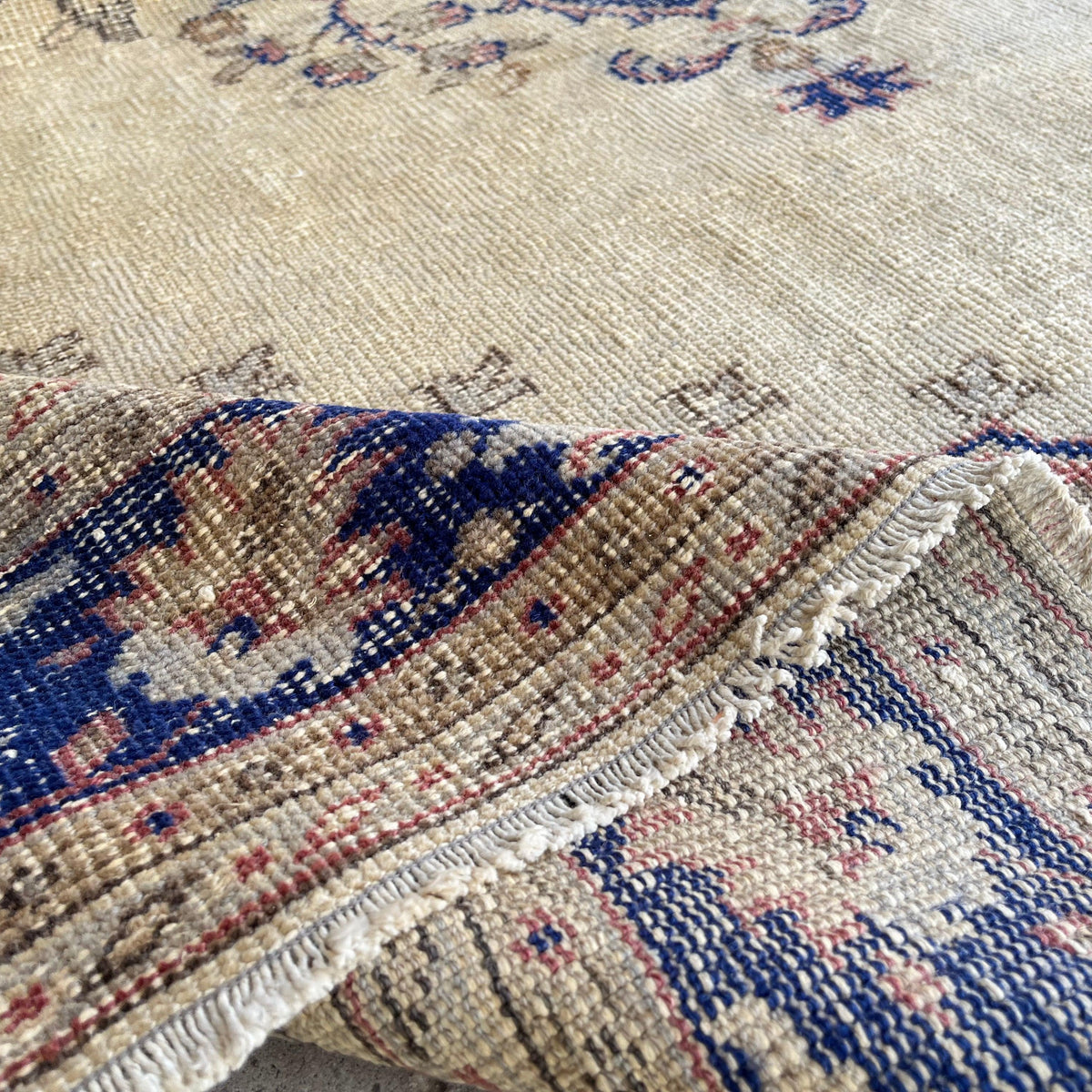Close-up of the blue vintage Turkish persian rug showing medallion details, hand-knotted weave, wool and cotton and low pile.