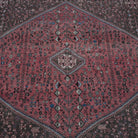 Close-up of the red vintage Turkish persian rug showing geometric details, hand-knotted weave, wool and cotton and low pile.
