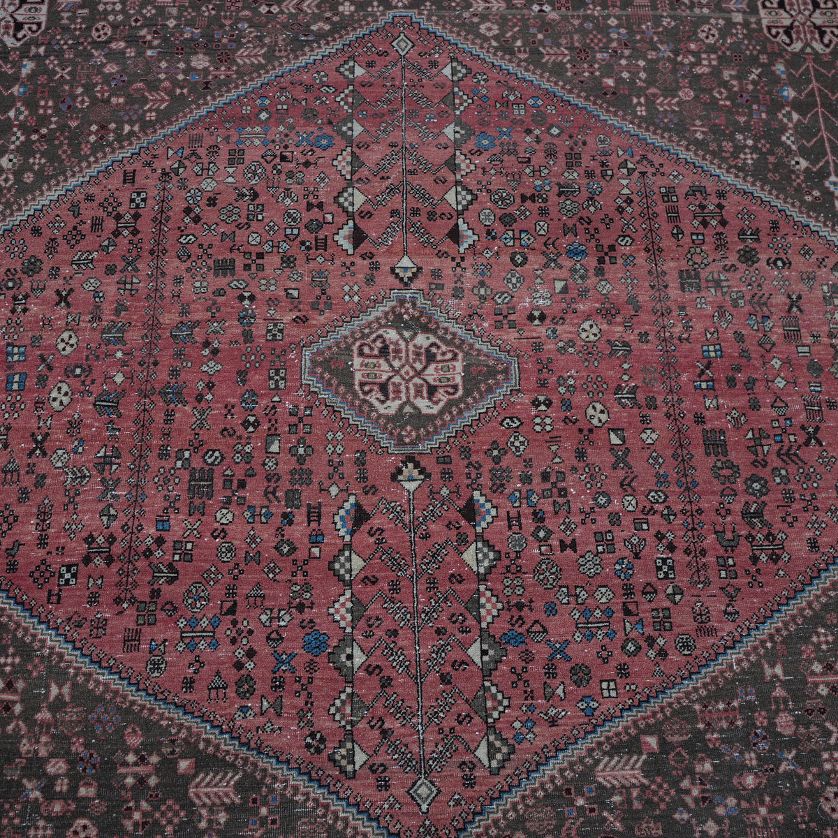 Close-up of the red vintage Turkish persian rug showing geometric details, hand-knotted weave, wool and cotton and low pile.