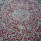 Close-up of the red vintage persian rug showing floral details, hand-knotted weave, wool and cotton and low pile.