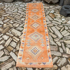 Orange 3' x 10' vintage persian runner rug in wool and cotton, shown on the floor.