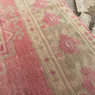 Close-up of the pink vintage Turkish persian runner rug showing traditional details, hand-knotted weave, wool and cotton and low pile.