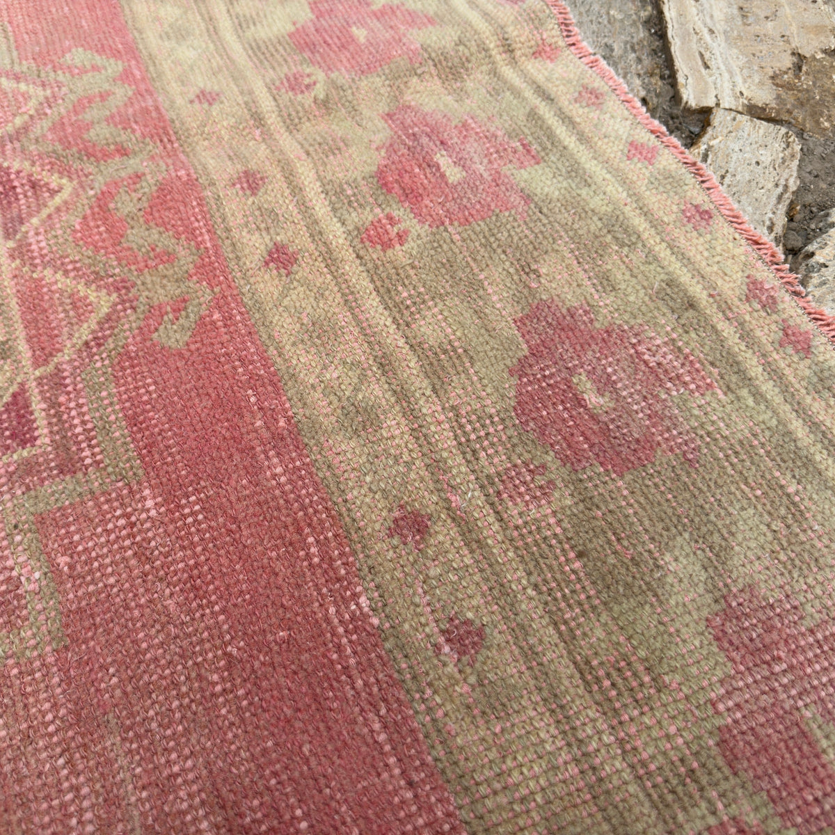 Close-up of the pink vintage Turkish persian runner rug showing traditional details, hand-knotted weave, wool and cotton and low pile.